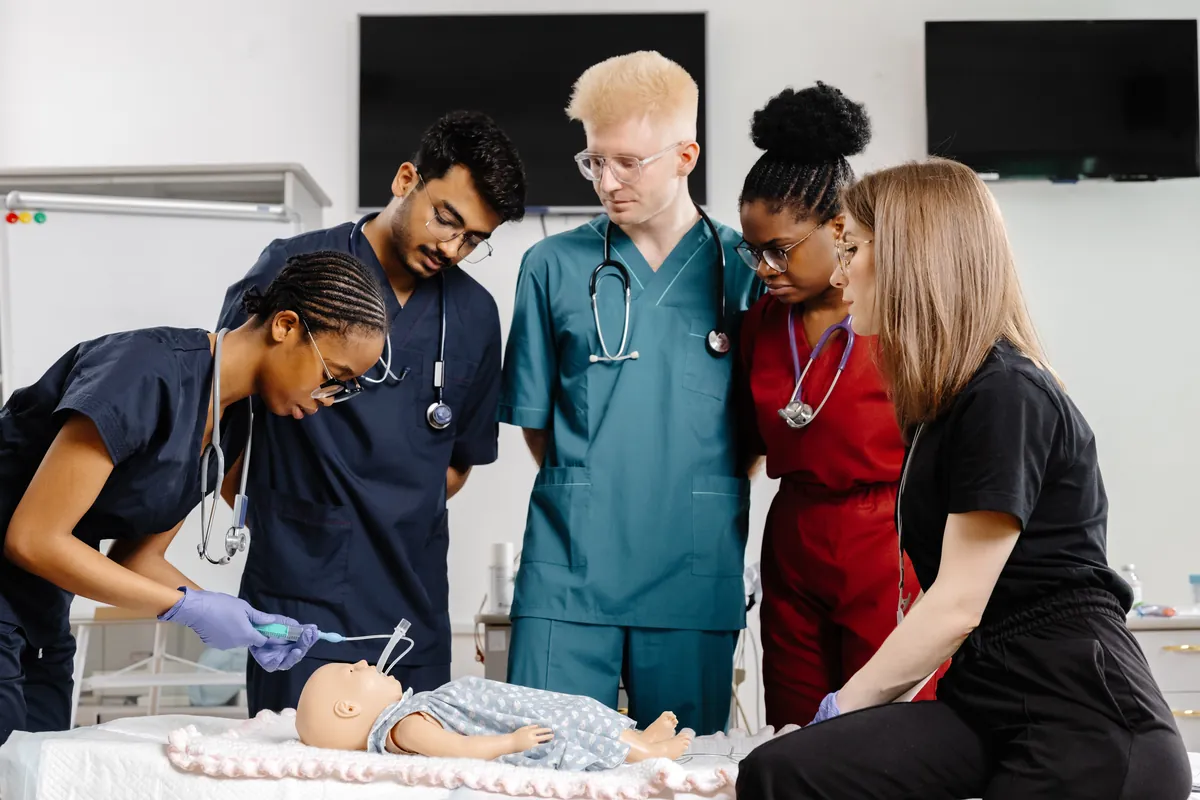 Diverse nursing students practising on a manikin in a bright simulation lab