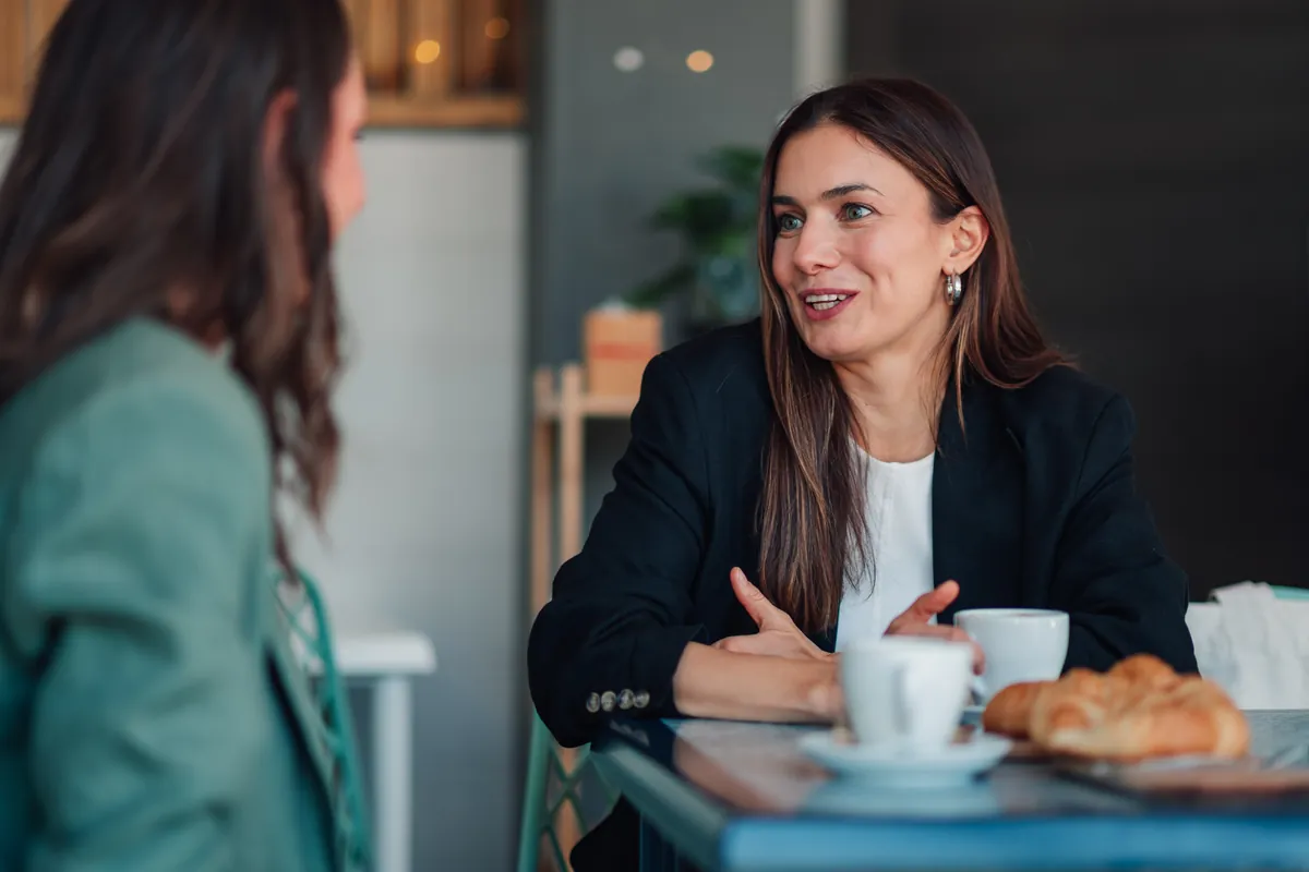 Professional woman smiling during a mentoring chat over coffee in a cafe