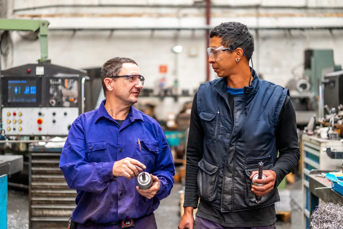 Instructor talking with a young machinist in an industrial workshop