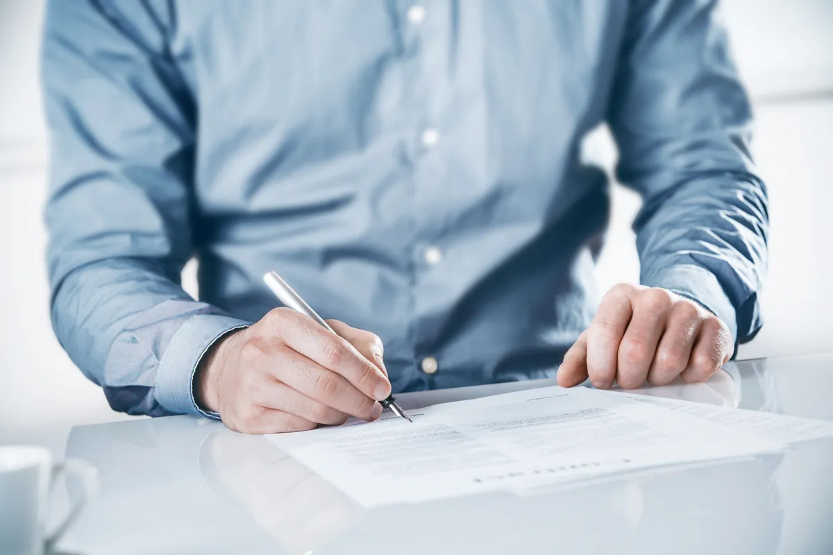 Hands reviewing a document with a pen on a bright desk