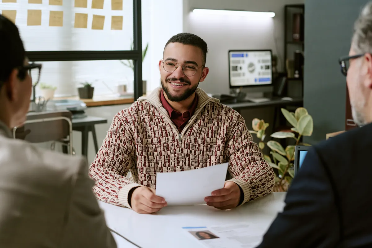 Smiling candidate holding papers while talking with an assessor