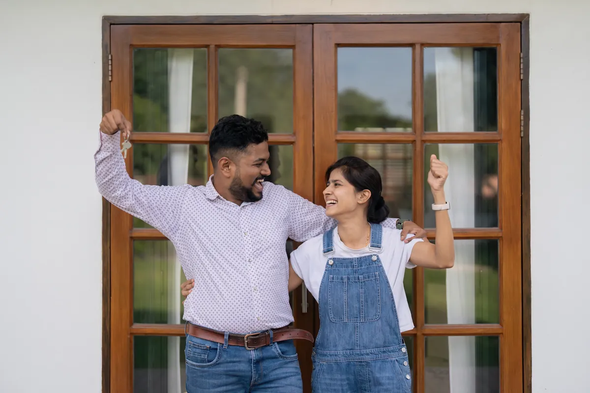 Couple celebrating with keys outside their new home