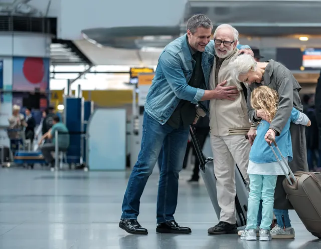 Elderly parents hugging family on arrival at the airport