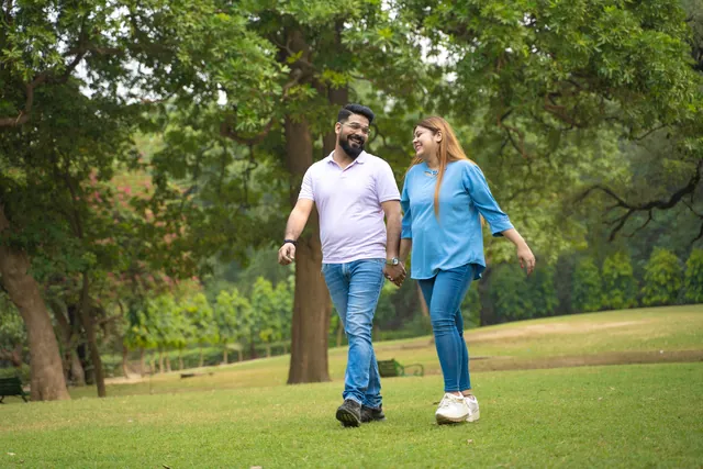Young couple walking hand in hand through a leafy park