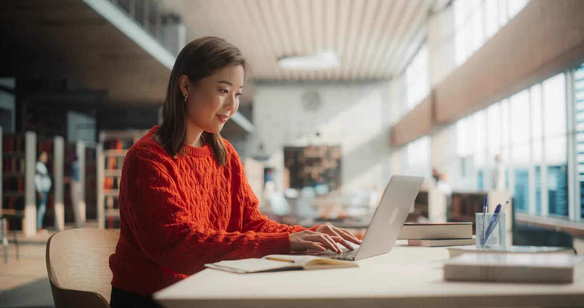 Student studying at a laptop in a bright modern library